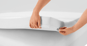 The corner of a mattress topper held up to show zipped cover